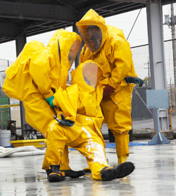 Two workers carrying another worker who has collapsed to be decontaminated