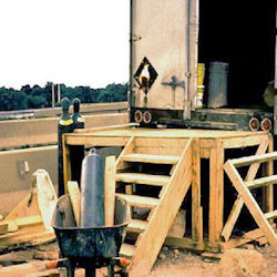 building construction site with two entry stairways and a barrell of used materials