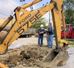 two workers standing near an excavator