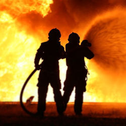 Image of two firefighters using a hose to spray water