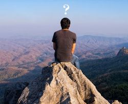 One person sitting on top of a hill with an imaginary question mark over his head