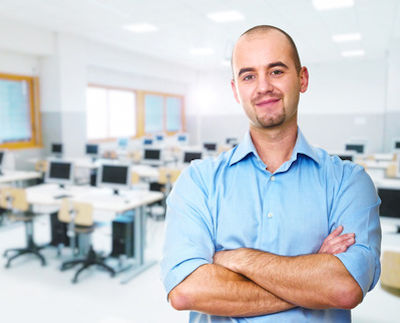 Worker standing in a classroom with arms crossed looking forward