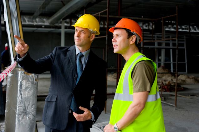 Manager pointing out object with worker looking on