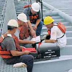 Competent person showing three workers about worksite safety