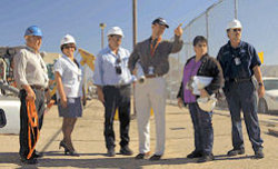 Five workers and one instructor standing together outside.