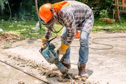 Worker bending over to use a jackhammer