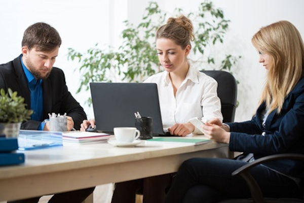 Three employees stitting at a table reviewing results of an inspection
