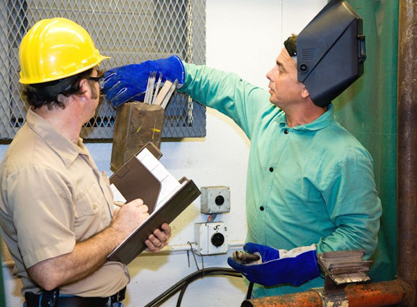 Two workers inspecting machinery for hazards