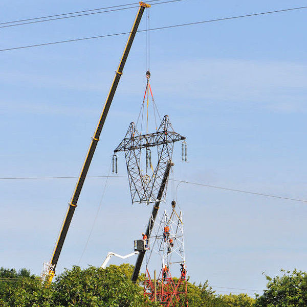 A crane lifting the upper portion of a high voltage tower 