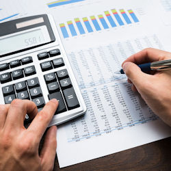 calculator and person recording numbers on a sheet of paper