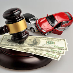 Two toy crashed cars and a hammer and gavel with money beneath the gavel