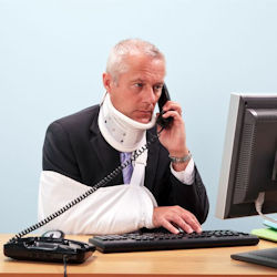 Person sitting at desk in front of computer wearing a neck brace