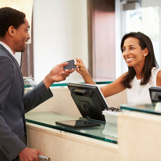 Person checking in at a desk presenting identification to clerk in front of computer