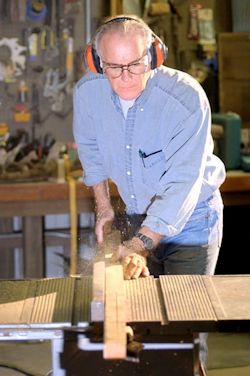 Worker using table saw in a shop area.