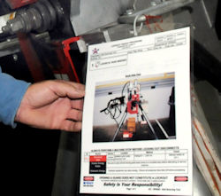 A worker looking at the lockout tagout procedures posted on the machinery.