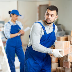 Male and female worker lifting bricks