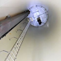 worker looking down a very long deep confined space.