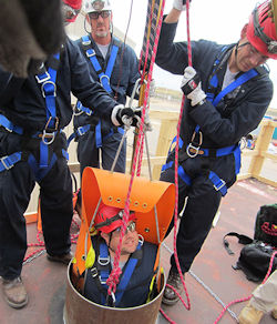 Three rescuers practice training with one worker being pulled up for a confined space rescue