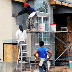 Three workers plastering house