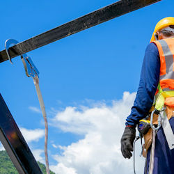 Worker on construction site using fall protection that has multiple deficiencies.