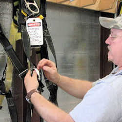 inspector checking webbing on fall protection equipment