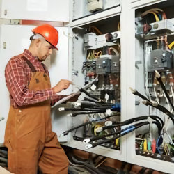 worker standing in front of two electrical panels noting electrical hazards
