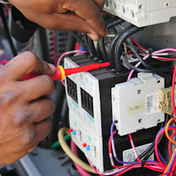 Electrician working near live circuits for testing.