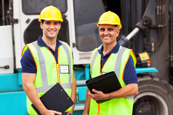 Two supervisors standing together both holding notebooks.