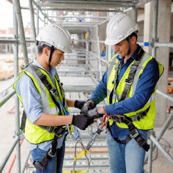 Trainer showing worker how to use a harness