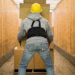 Image of an employee using a back belt while lifting heavy boxes