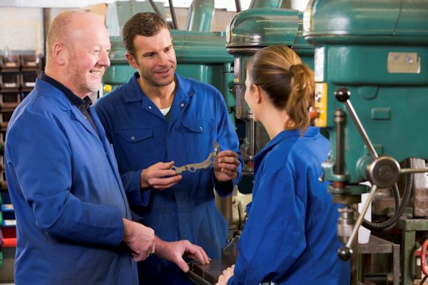 Employee conducting on-the-job training to two learners.