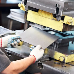 Image of worker using a sheet metal press that is in need of a safety guard