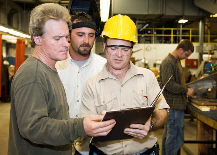 Image of two machine operators talking with supervisor