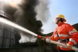 Image of firefighter spraying flames hose.