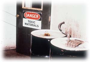 Entry door with a sign danger toxic materials and two black drums.