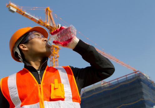 Worker in hot sun drinking bottled water.