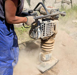 Worker using ground stamping machine that has a lot of vibration.