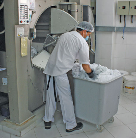 employee with gloves and mask sorting medical laundry