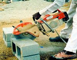 Worker using saw to cut cement blocks producing dangerous silica dust