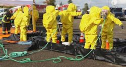 Image of six employees in full PPE moving through a decontamination station.