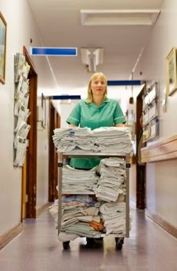 Image of worker pushing heavy cart of medical linen supplies