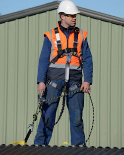 Workers wearing a fall restraint system while standing on top of a roof.