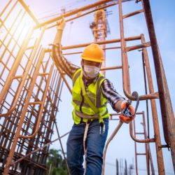 Worker strapping fall protection to scaffold