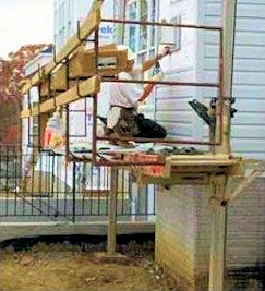 Workers using a pump jack scaffold while installing siding.