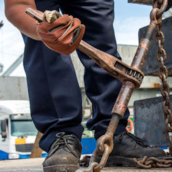 Worker using a wrench for tightening a turnbuckle.