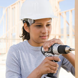 Worker outside in construction site using a hand drill