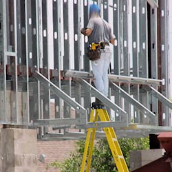 worker standing on the very top of ladder