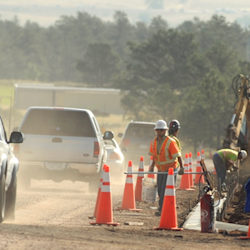 Dusty road side work site with employee and barrier cones