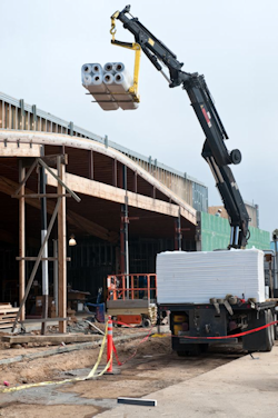 crane placing materials on roof of work site