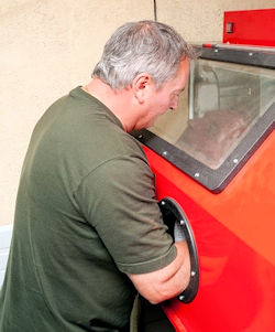 Image of worker using an enclosure to isolate dust and work with hazardous silica exposure.